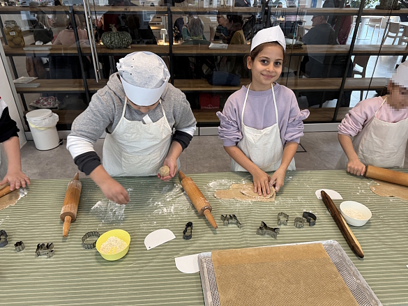 Schülerinnen und Schüler rollen den Teig aus