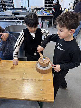Schülerinnen und Schüler mahlen Getreide