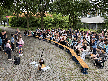 Die Schulgemeinschaft sitzt draußen bei der Bühne