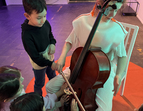 Schüler:innen dürfen auf einem Cello spielen und die Schwingungen der Töne spüren