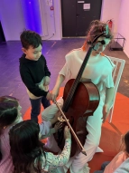 Schüler:innen dürfen auf einem Cello spielen und die Schwingungen der Töne spüren