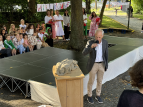 Während Walli der Drache interviewt wird, warten die Zweit- und Drittklässler:innen gespannt auf ihre Patenkinder