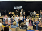 Schülerinnen und Schüler singen und musizieren in der Aula der GSO