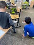 Schüler nutzen eine Kleiderbügelwaage